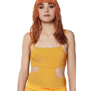 Woman wearing a mustard yellow dress with cut-out design on a plain background